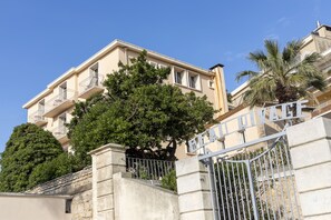 A multi-story building with balconies, a gated entrance, and a palm tree. - Résidence Le Beau Rivage (Bandol)