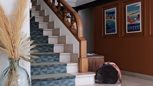 A staircase with geometric patterned steps, a wooden handrail, and a vase with dried plants. - Résidence Le Beau Rivage (Bandol)