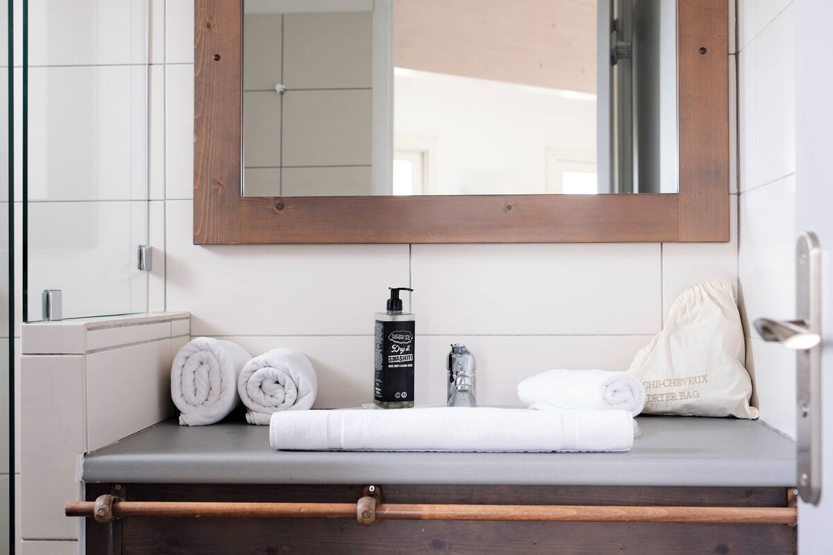 Une salle de bain avec un miroir encadré en bois, un porte-serviettes et une serviette posée sur le comptoir.
