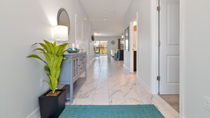 A hallway with a potted plant, a console table with a lamp, and a door leading to another room. - ChampionsGate, 9 Bed Luxury Exec Villa, Sleeps 26, Pool & Spa Heat Included (ChampionsGate)