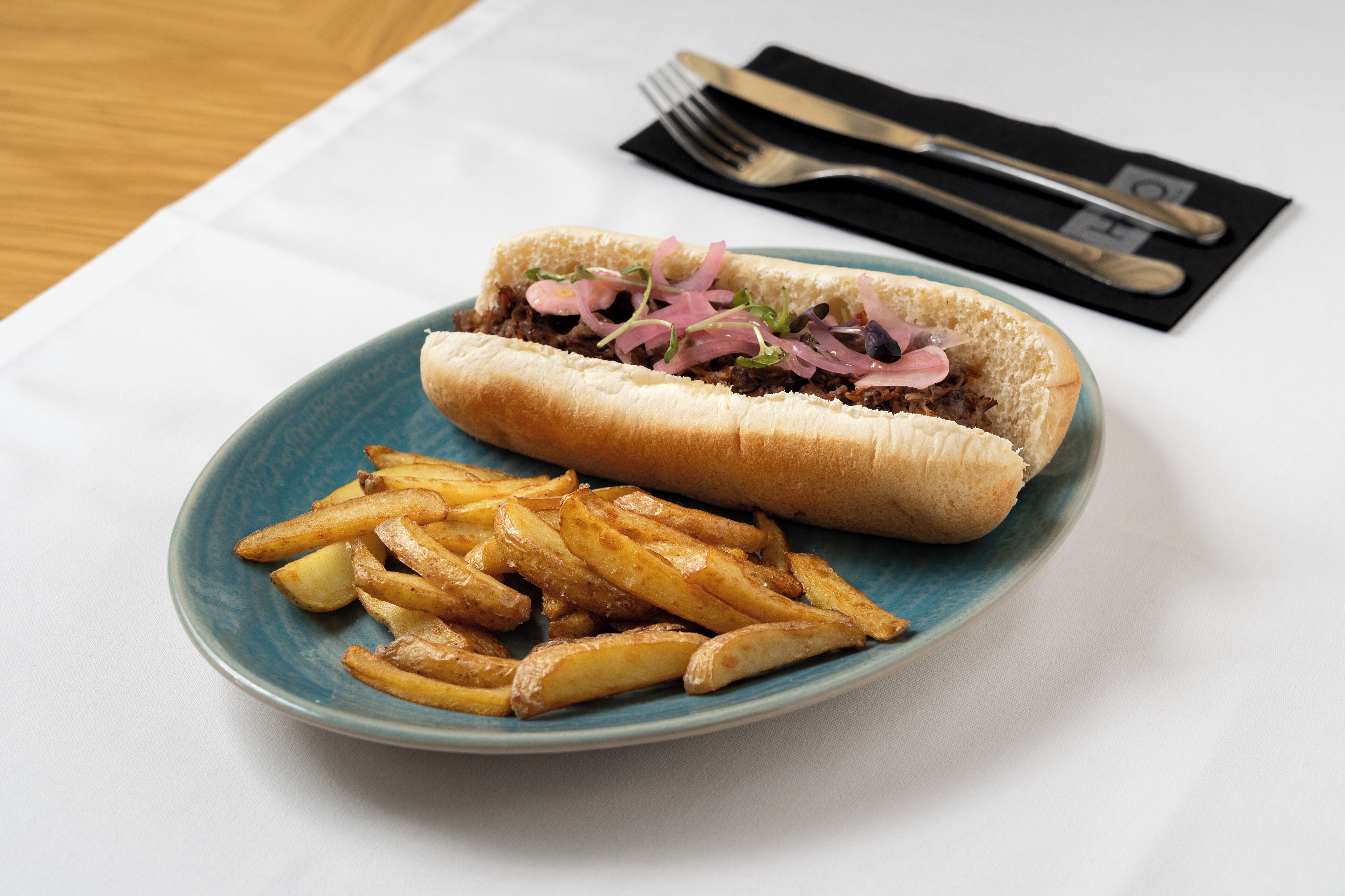 Un plato con un sándwich y papas fritas sobre un plato azul.