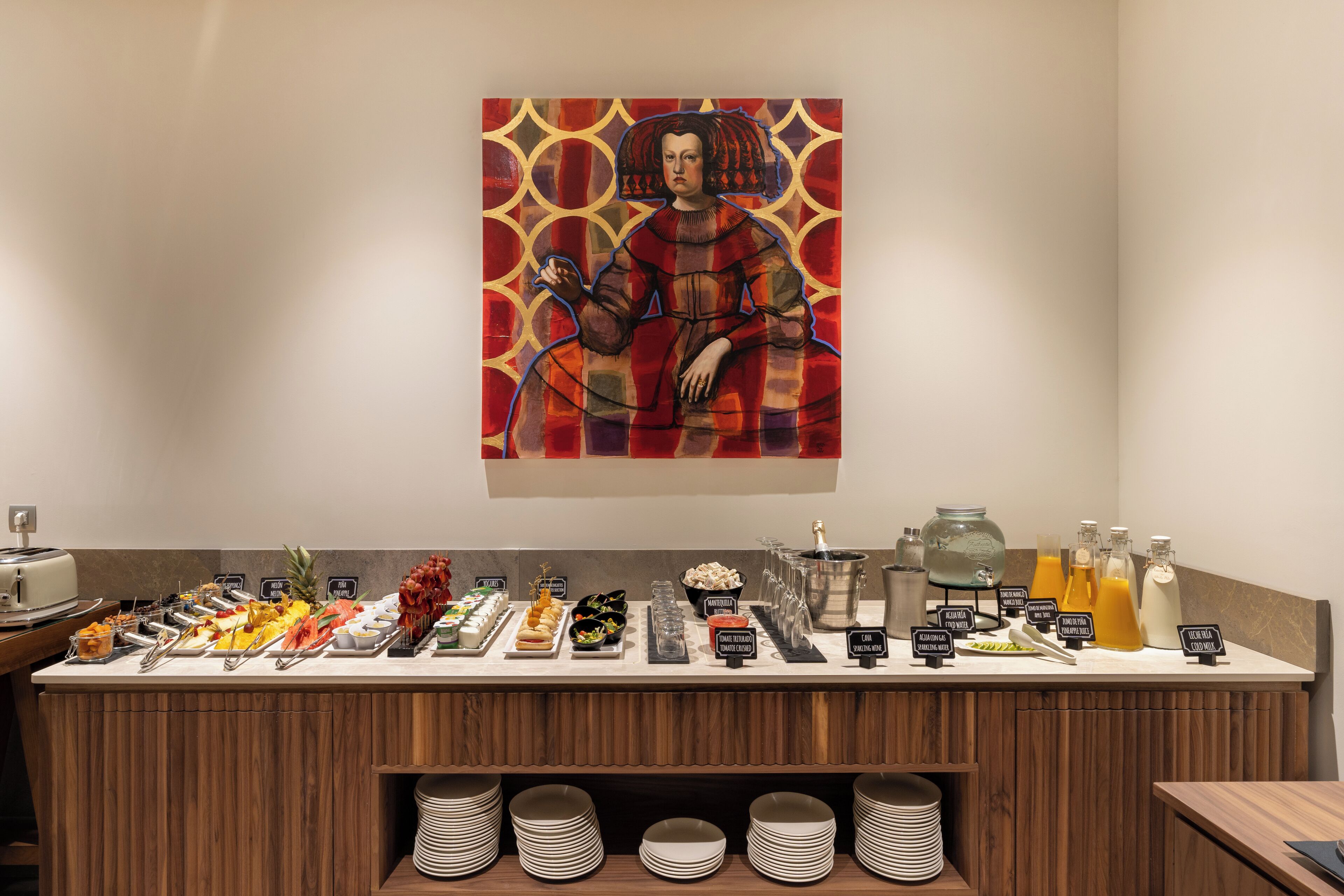 A buffet with various food items and beverages, including a pineapple, a bowl of fruit, and a bottle of orange juice.
