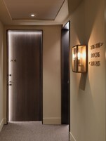 En gang med en trædør mærket 204, en vægmonteret lampe og skilte der viser vej til værelser 206, 208 og 204, 205.