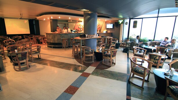 A spacious indoor area with multiple seating arrangements, a bar area, and a projection screen. - Hotel La Vinci (Dhaka)