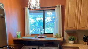 Une cuisine compacte équipée de deux machines à laver, d’un tabouret de bar, d’un lustre et offrant une vue par la fenêtre.