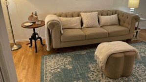 Un salon chaleureux avec un canapé beige, un tapis à motifs et une citation encadrée accrochée au mur.