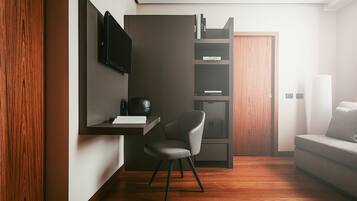 Una habitación moderna con suelo de madera, un sofá gris, un televisor negro montado en la pared y una puerta de madera.