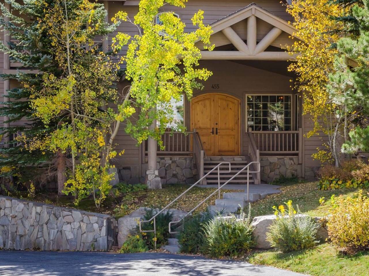 A two-story building with a stone facade, a wooden front door, and a stone staircase leading to the entrance.