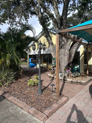 A building with a porch, outdoor seating, and a tree. - The Villa at Harbor House (Safety Harbor)