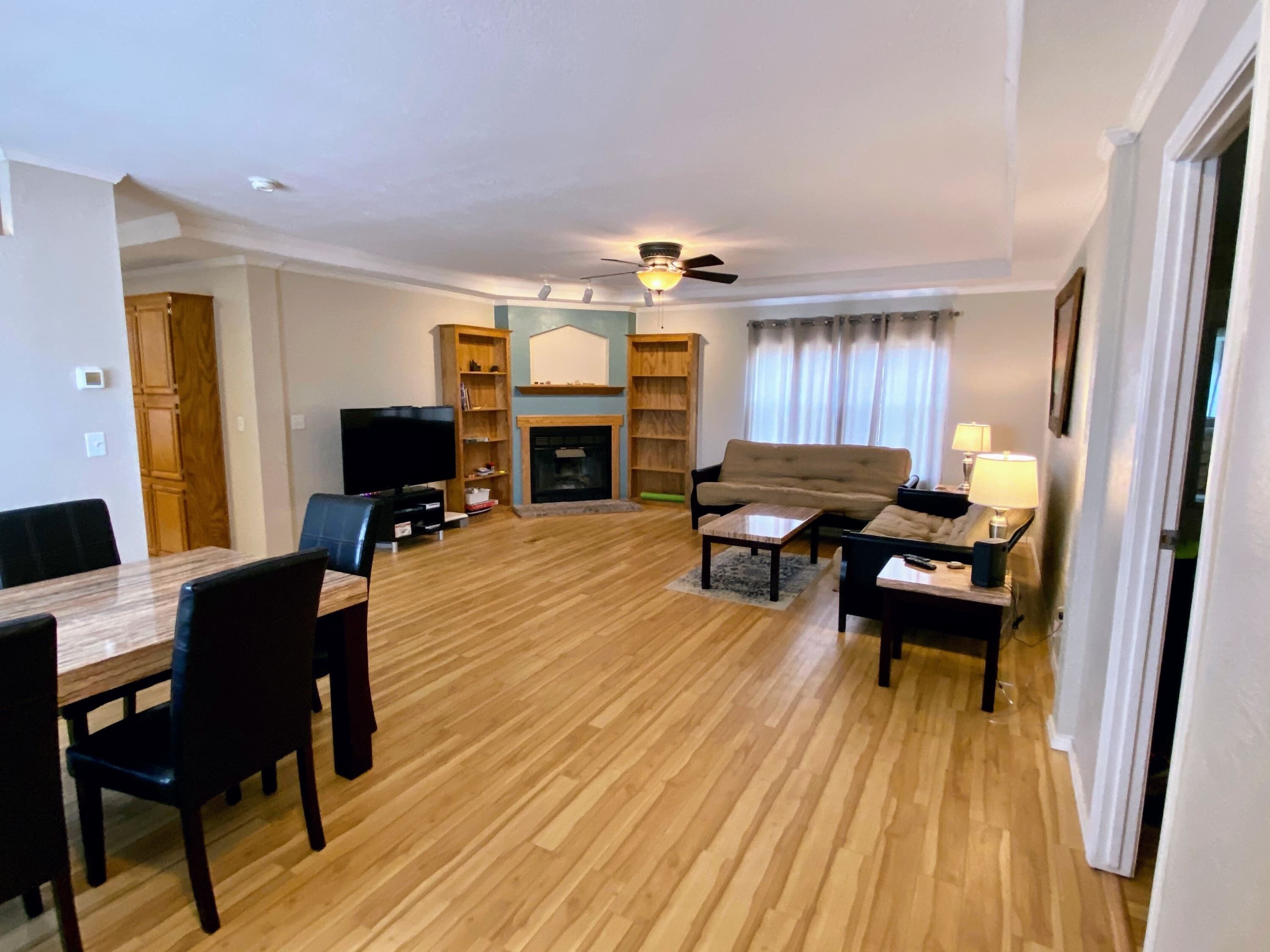 Ein Wohnzimmer mit einer Couch, einem Couchtisch, einem Fernseher, einem Kamin und Holzböden.