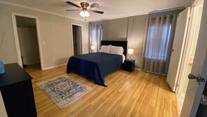 A bedroom with a bed, a ceiling fan, a nightstand, a rug, and a door. - Cactus Corazón: Comfortable, Spacious & Secluded (Alpine)