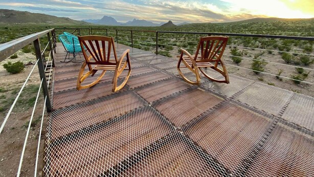 A balcony with two wooden rocking chairs and a blue chair, overlooking a desert landscape with mountains in the distance. - Cactus Corazón: Comfortable, Spacious & Secluded (Alpine)