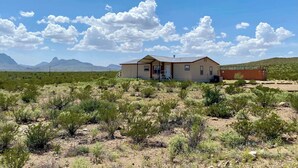 A single-story house with a flat roof, a front porch, and a visible garage. - Cactus Corazón: Comfortable, Spacious & Secluded (Alpine)