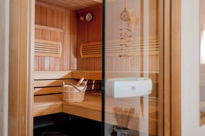 Un sauna avec des bancs en bois, un seau en bois et un panneau de commande blanc.