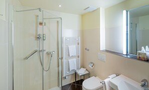 A modern bathroom with a glass shower enclosure, a white toilet, a bathtub, and a towel rack.