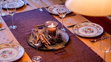 A dining table set with floral plates, wine glasses, and a candle centerpiece.
