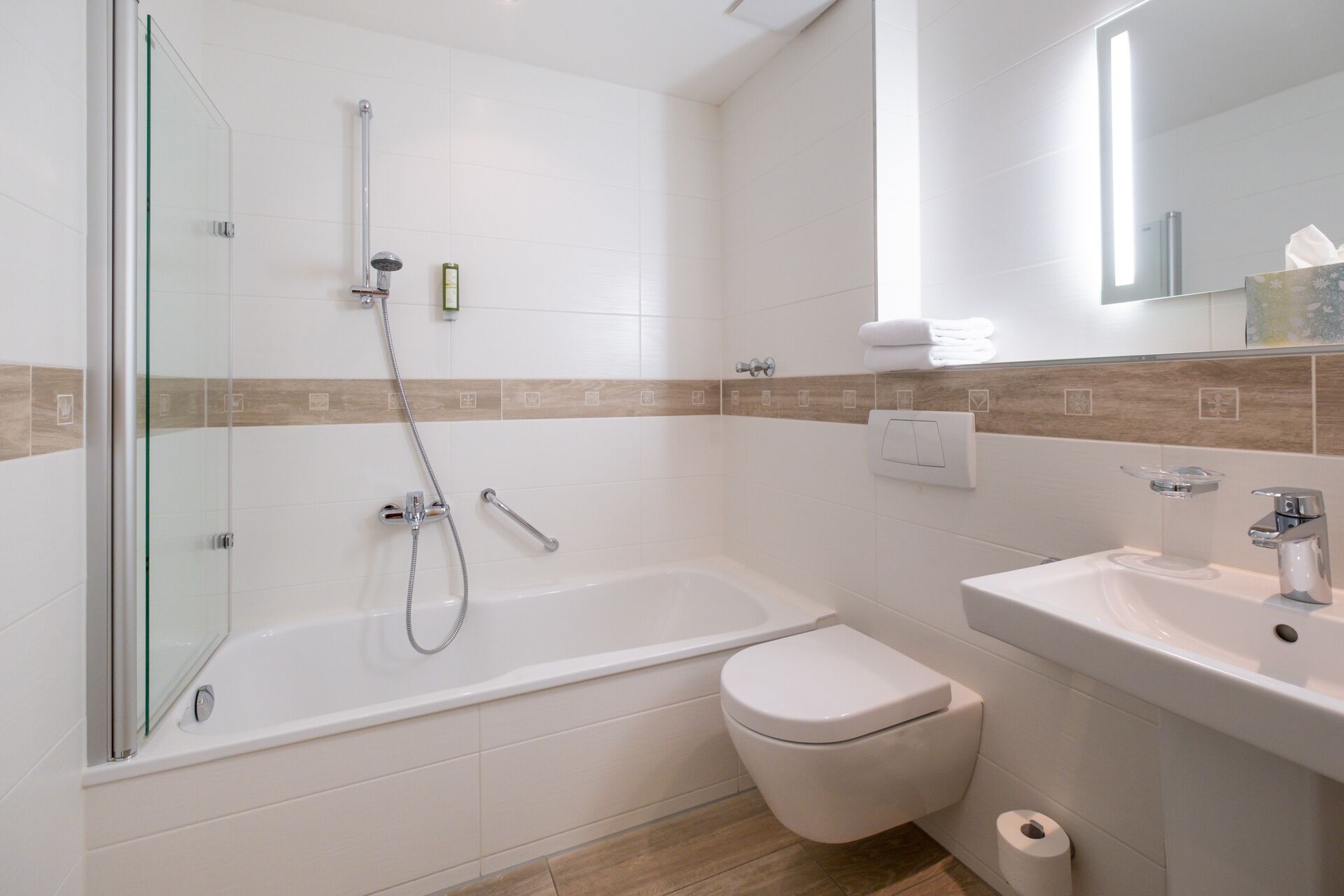 A modern bathroom with a glass shower enclosure, a bathtub, a toilet, and a sink.