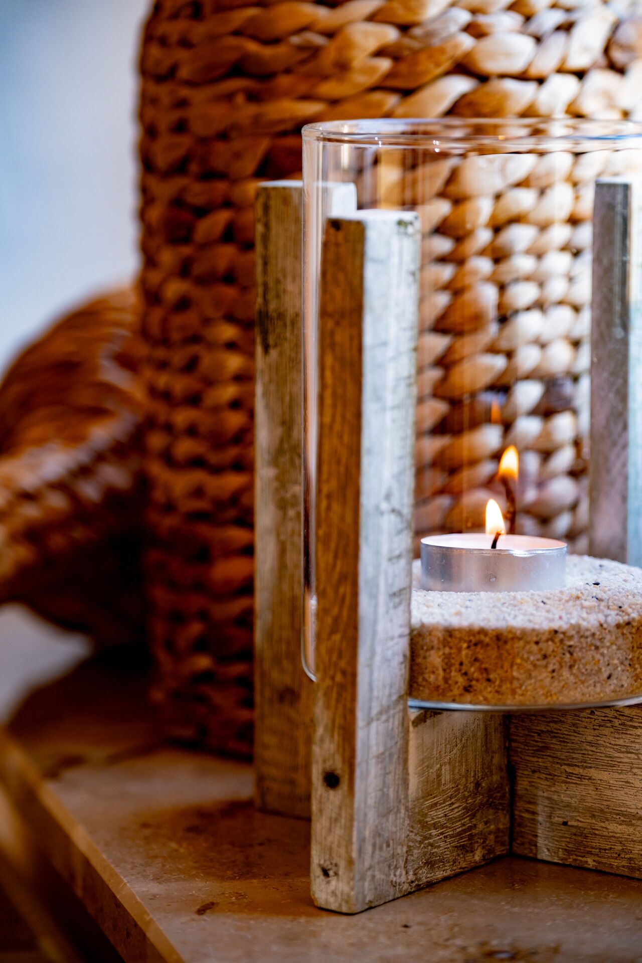 A candle in a glass holder on a wooden surface.