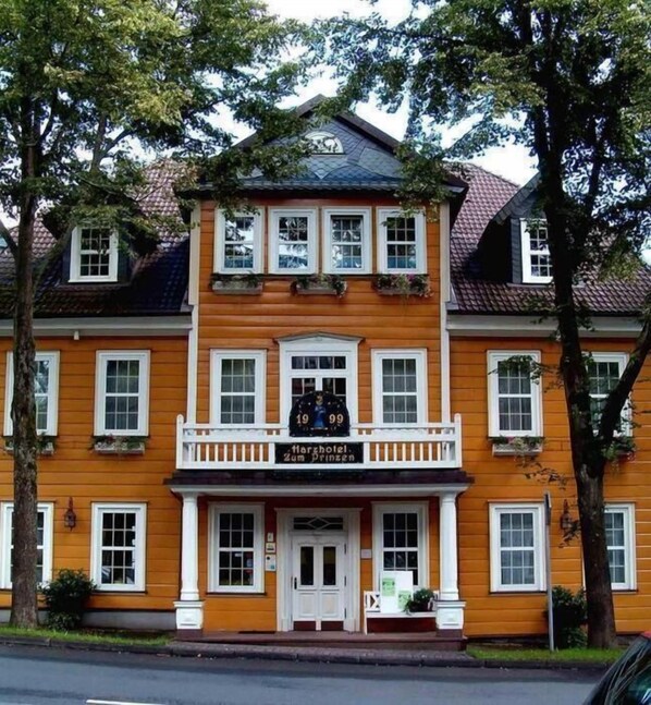 A two-story building with a central balcony, a sign reading "Herzhotel Zum Prinzen," and a traditional European architectural style.