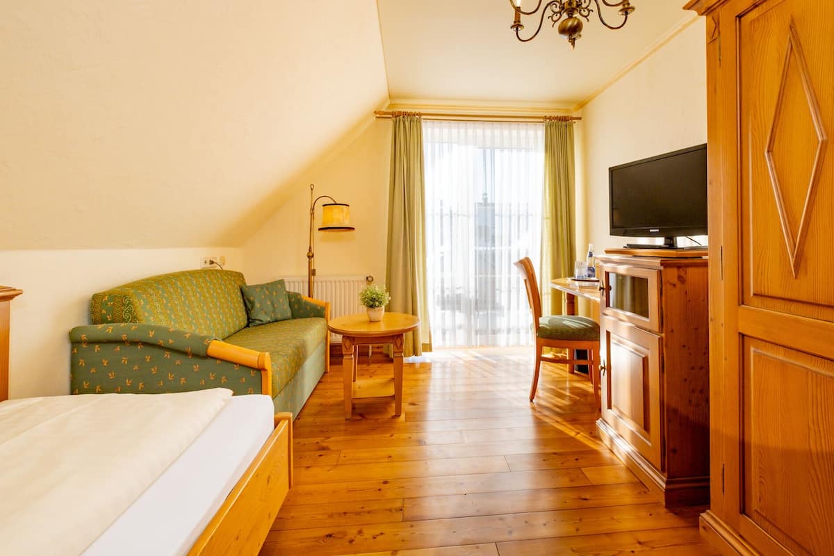 Ein Hotelzimmer mit Bett, Sofa, Fernseher und Holzschrank.