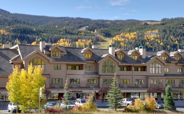 A hotel with a row of rooms featuring large windows and a mountain backdrop. - Top floor condo, mountain views, steps to village, free shuttle, 1 min to slopes (Keystone)