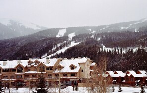 A lodge with multiple buildings, surrounded by snow-covered mountains and trees. - Top floor condo, mountain views, steps to village, free shuttle, 1 min to slopes (Keystone)