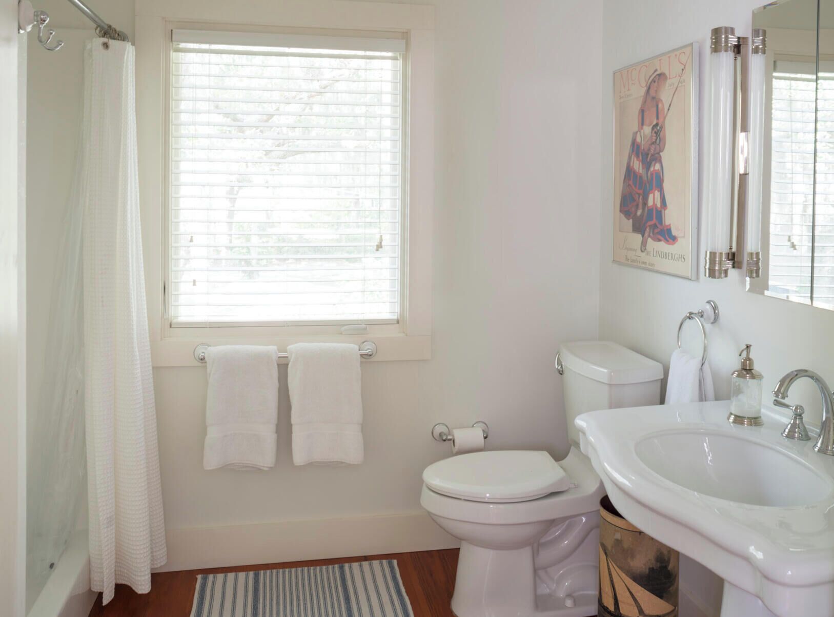 Une salle de bain avec des toilettes, un lavabo et une fenêtre. Deux serviettes sont accrochées au mur.