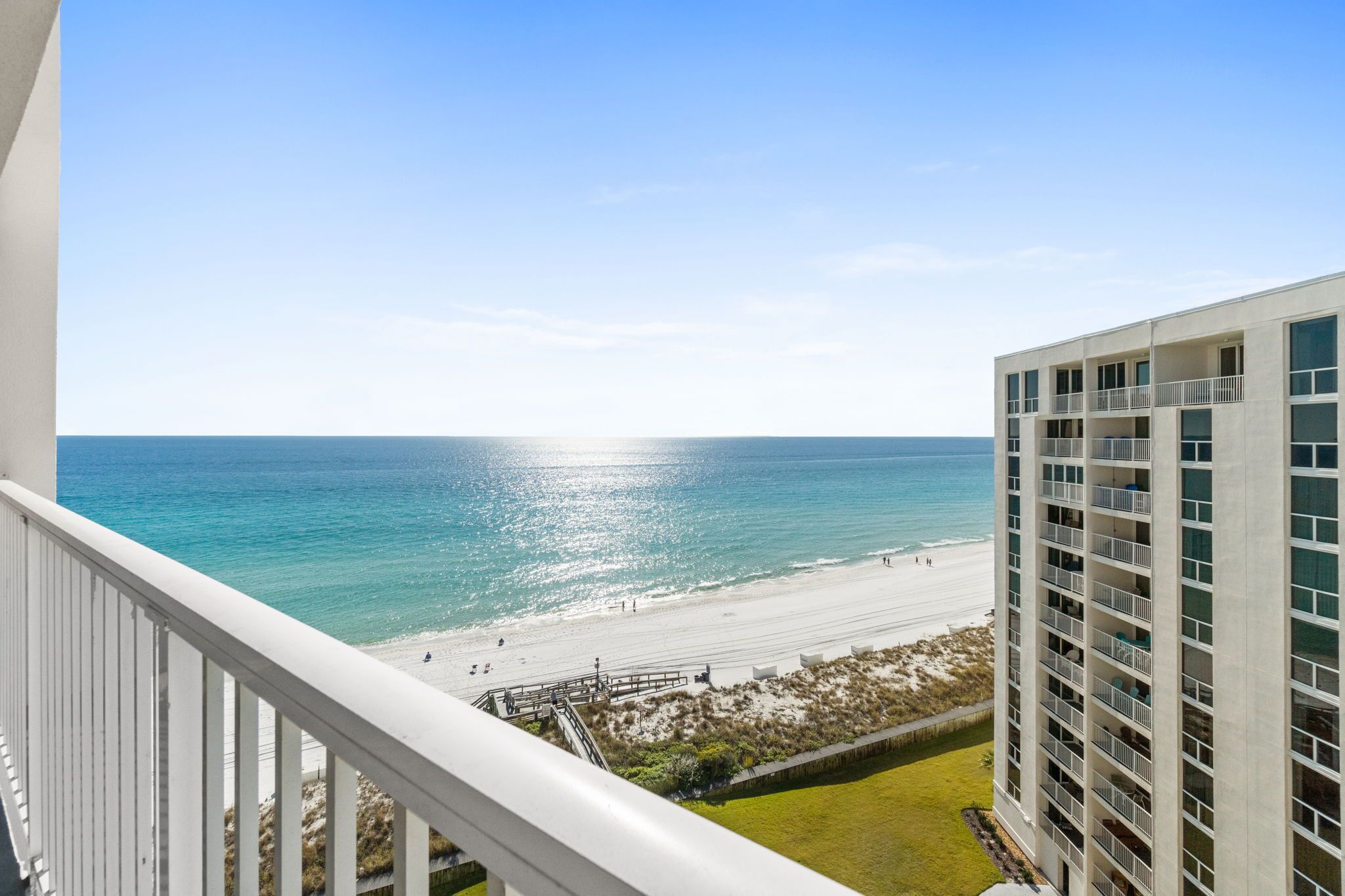A high-rise hotel with a balcony overlooking a beach.