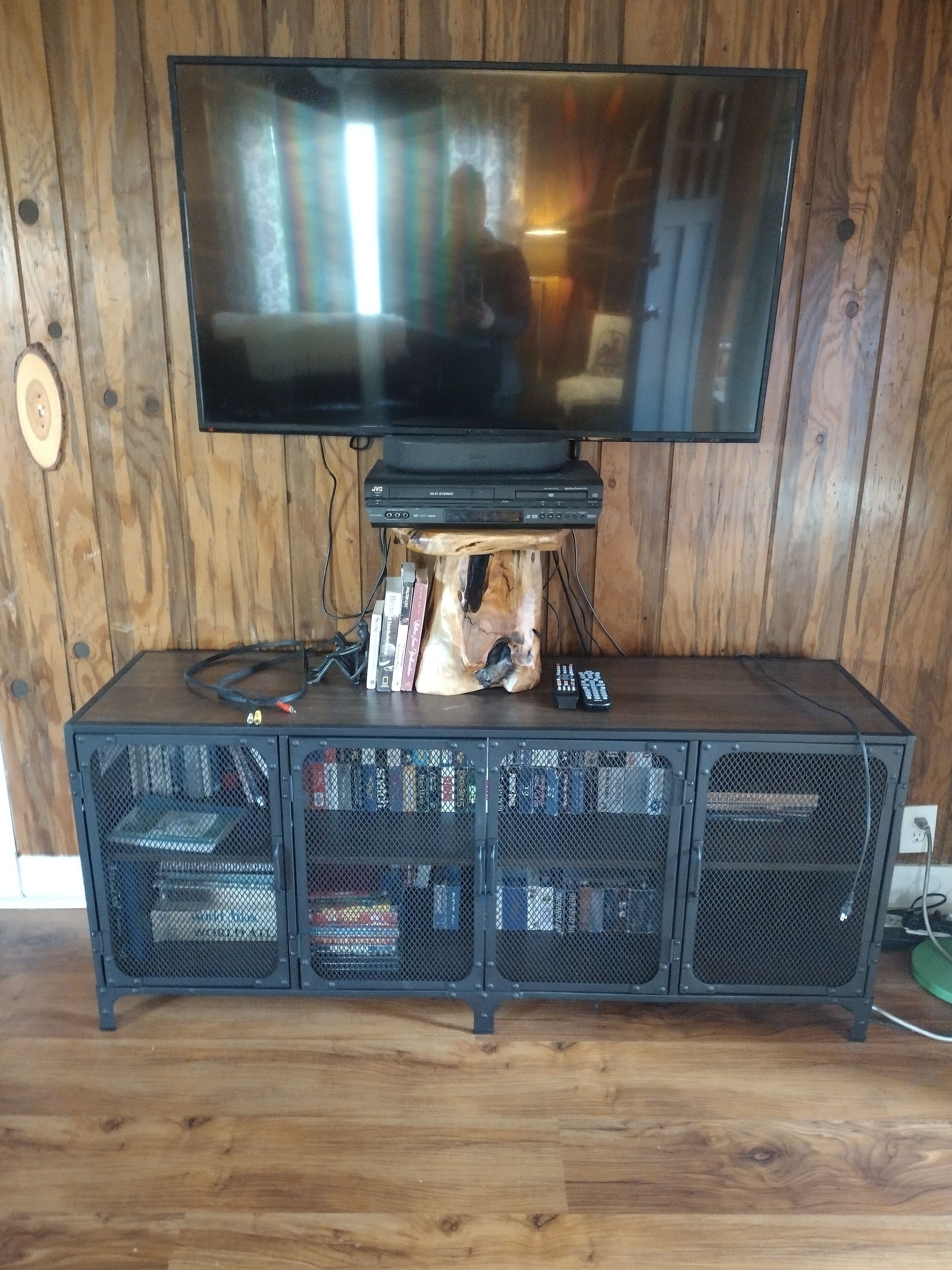 A wooden entertainment unit with a flat-screen TV mounted on top, a dog-shaped speaker, and a collection of DVDs and books.
