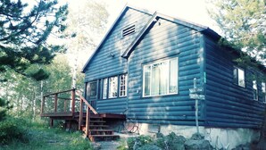 A rustic cabin with a wooden deck and stairs leading to the entrance. - Cozy Cabin minutes from Yellowstone, fly fishing, skiing and snowmobiling.  (Island Park)