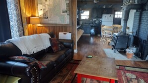 A cozy living room with a leather sofa, a wooden coffee table, and a map on the wall. - Cozy Cabin minutes from Yellowstone, fly fishing, skiing and snowmobiling.  (Island Park)