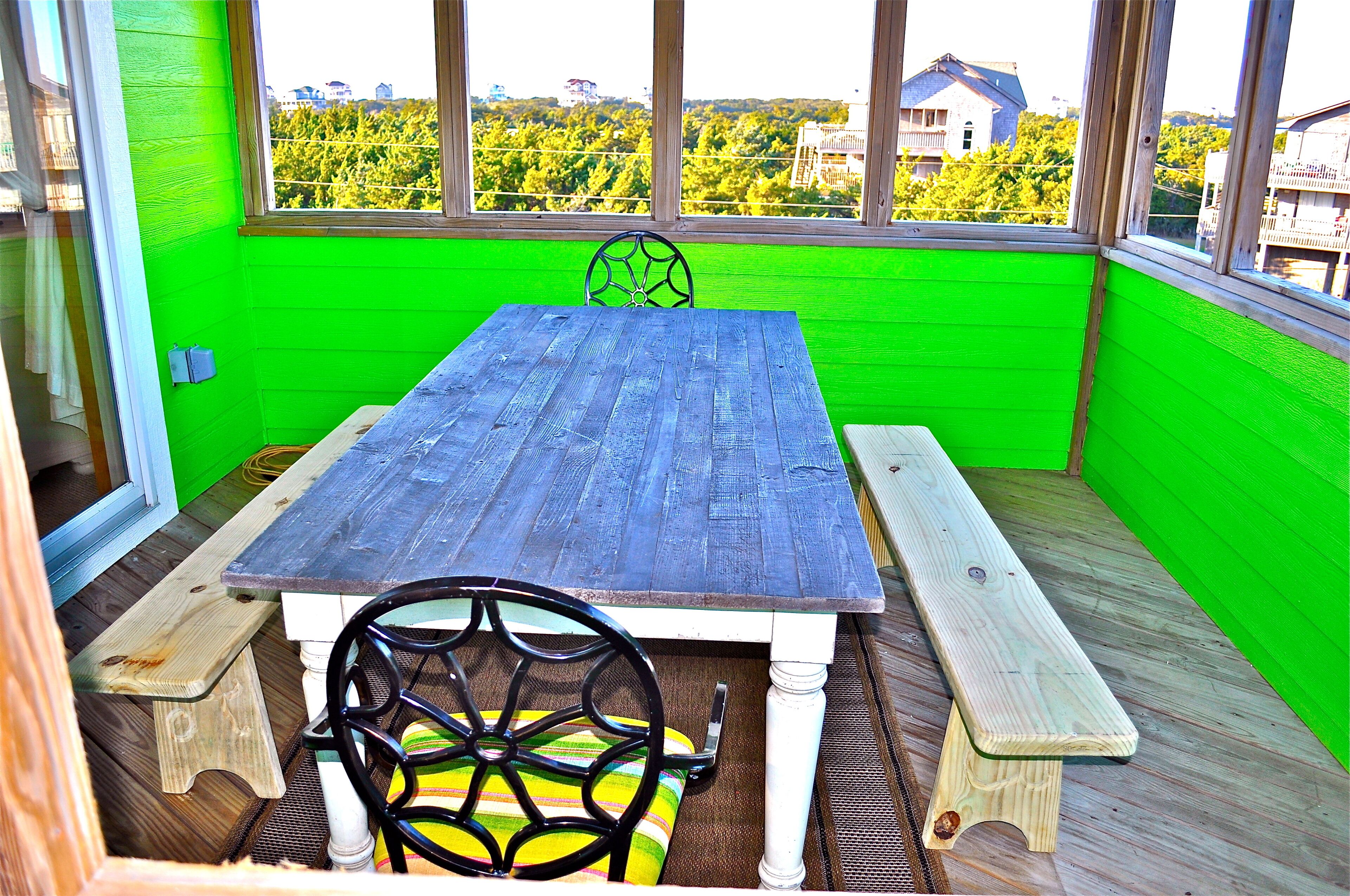 A wooden table with benches, a chair, and a view through large windows.