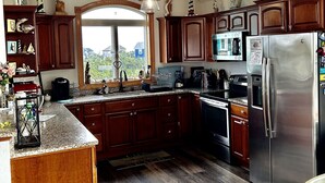 A kitchen with wooden cabinets, a stainless steel refrigerator, a microwave, and a large window. -  360 views new outside, air purf, pool best beds always updating. Booking 2025 (Avon)