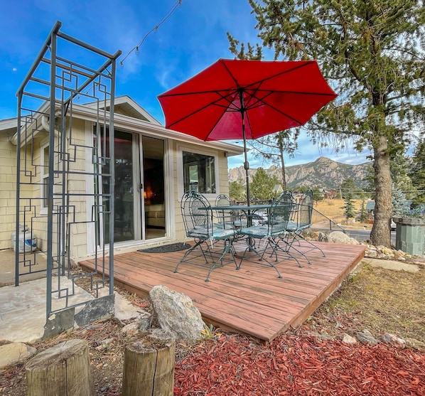 A patio with a red umbrella, outdoor furniture, and a view of mountains.