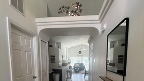 A hallway with a tiled floor, white walls, a ceiling fan, and a mirror on the right. - Glenbrook Retreat-Come in as Guests and Leave as Friends (Clermont)