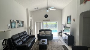 A spacious living room with a black leather sofa, a coffee table, and a television. - Glenbrook Retreat-Come in as Guests and Leave as Friends (Clermont)