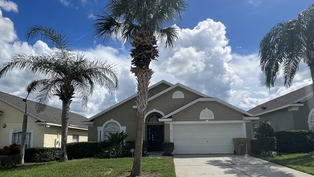 A residential house with a garage, a driveway, and a lawn with palm trees. - Glenbrook Retreat-Come in as Guests and Leave as Friends (Clermont)