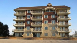 A multi-story hotel with balconies, a stone facade, and a beach view.