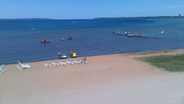 A beach with several boats on the water and lounge chairs on the sand.