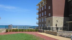 A multi-story hotel with a stone facade, a balcony on the second floor, and a view of the beach and ocean.