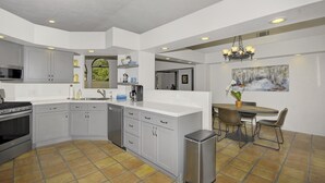 A modern kitchen with grey cabinets, a stainless steel refrigerator, and a dining area with a table and chairs. - Casa de Saltillo - single level home, gorgeous views, close to trails. (Sedona)
