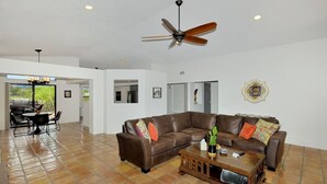 A spacious living area with a brown leather sectional sofa, a wooden coffee table, and a ceiling fan. - Casa de Saltillo - single level home, gorgeous views, close to trails. (Sedona)