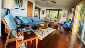Un salón espacioso con un sofá azul, una mesa de centro de madera y una zona de comedor con sillas y una mesa.
