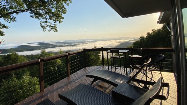 Una terraza de madera con vistas a un bosque y montañas.