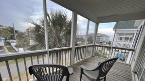A covered porch with two chairs and a view of the neighborhood. - Professionally Decorated,100 Yards to Beach, Shared Pool (Surfside Beach)