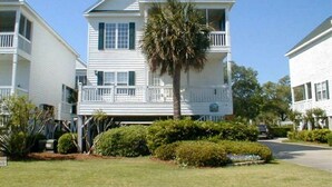 A two-story white house with a balcony, surrounded by greenery and a clear sky. - Professionally Decorated,100 Yards to Beach, Shared Pool (Surfside Beach)