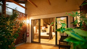 Une chambre avec une grande porte-fenêtre coulissante, un lit, une chaise et une table de chevet.