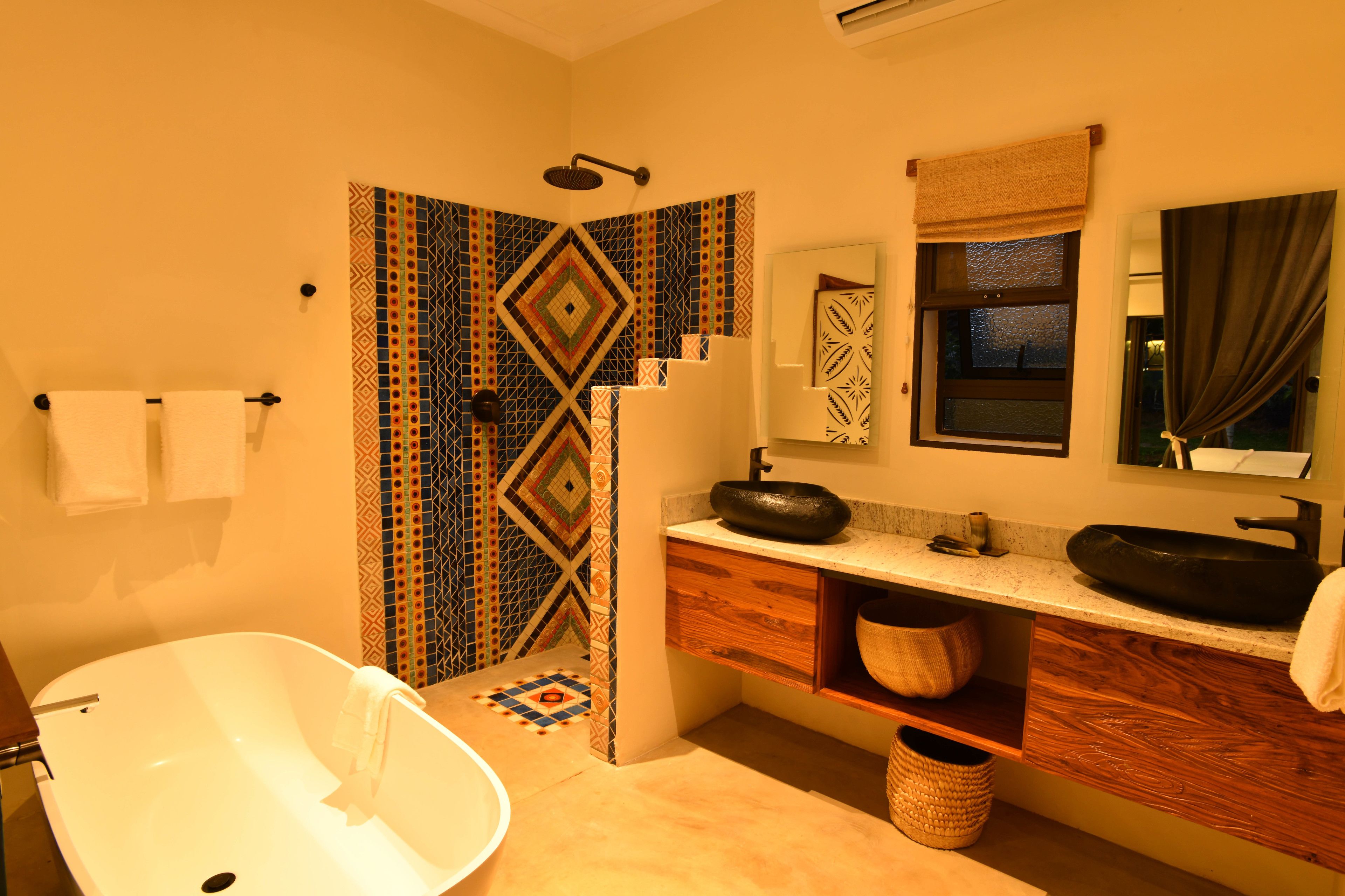 Une salle de bain avec une baignoire sur pieds, un lavabo avec un grand bac, un miroir et des rideaux de douche à motifs.