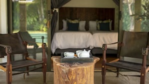 Une chambre avec deux lits, une table en bois sur laquelle se trouve un plateau avec un service à thé, et deux chaises.
