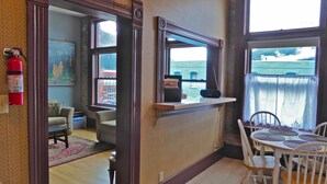 A room with a wooden floor, a dining table with chairs, a mirror, and a view of the sea through a window. - Studio Loft in historic Silverton Building (Silverton)